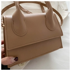 Close-up of a camel PU leather handbag with dual handles and matching crossbody strap