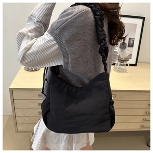 Detail of black nylon moon bag with pleated scrunchie strap shown in a lifestyle scene