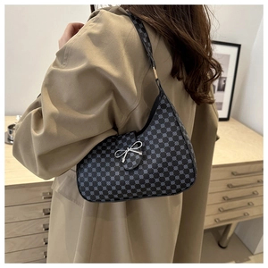 Detail of vintage pattern hobo bag with a silver bow clasp on a beige trench coat