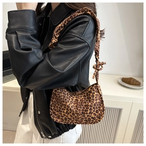 Detail of leopard print canvas underarm bag showing gathered strap and decorative knot