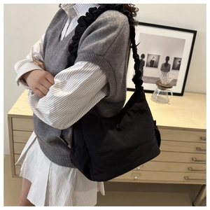 Close-up of black nylon hobo bag featuring a distinctive pleated ruffle shoulder strap