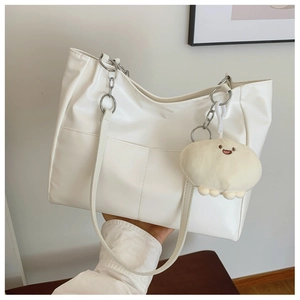 Detail of white PU leather tote with silver metal rings and cute plush charm pendant