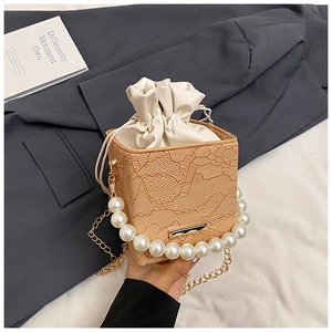 Detail of beige lace handbag with large pearl handle and gold chain shoulder strap