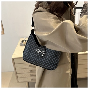 Detail of grey polka dot crescent bag with silver butterfly buckle and leather strap