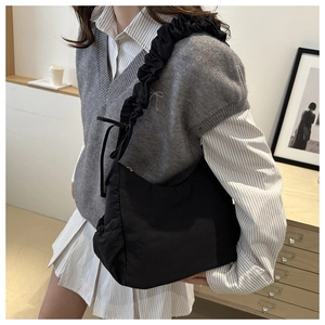 Detail of black nylon cloud bag featuring pleated shoulder strap and ribbon bow accent