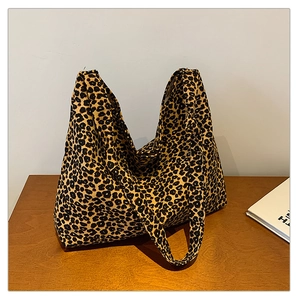 Close-up of leopard print tote bag fabric texture with wide shoulder strap on wooden table