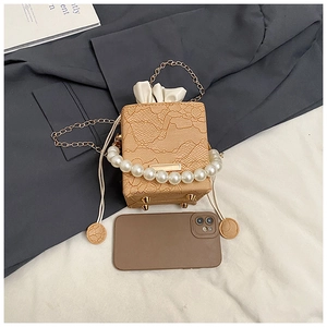 Detail of lace box bag featuring pearl handle, gold chain strap and drawstring closure