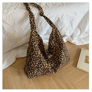 Detail of leopard print tote bag with knotted shoulder strap on light wood floor