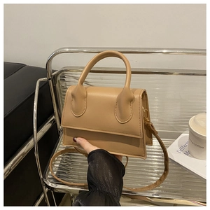 Detail of khaki leather handbag featuring circular handle and premium stitching quality