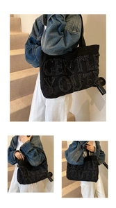 Dettaglio del ricamo Gentle Youth e dei bordi sfrangiati sulla borsa tote in denim nero