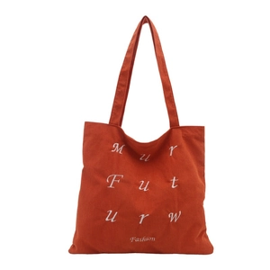 Orange corduroy tote bag with white letter embroidery and fashion text on white background