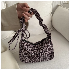 Detail of leopard print baguette bag featuring ruffled handle and decorative bow tie