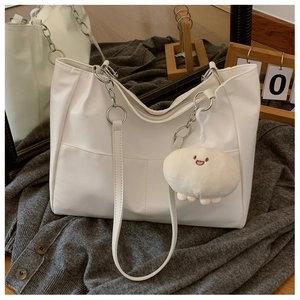 Detail of white PU leather tote bag with silver chain strap and plush keychain