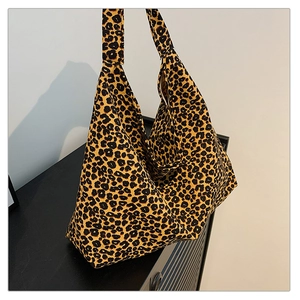 Detailed view of the large leopard print tote bag placed on a sleek black wooden surface