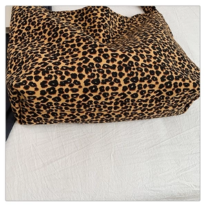 Top view of large leopard print canvas tote bag with wide bottom on white fabric