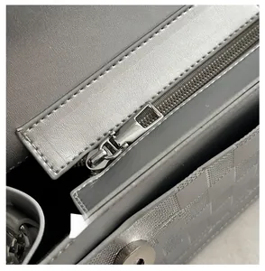 Macro detail of silver shoulder bag showing smooth metal zipper and textured plaid fabric