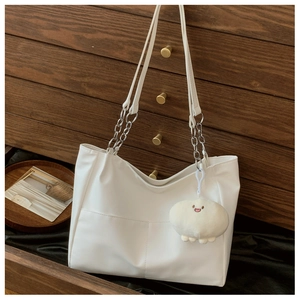 Detail of white tote bag featuring metallic chain strap and plush cloud charm accessory