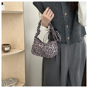 Detail of leopard print handbag with pleated handle and elegant ribbon knot decoration