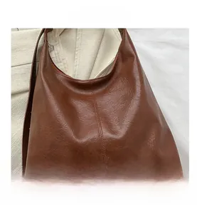 Close-up of deep brown large tote bag showing textured PU leather and fine stitching details