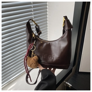Detail of dark brown crescent bag with embossed texture and cute bear charm pendant