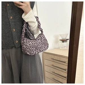 Detail of leopard print baguette bag featuring a unique gathered ruched handle design