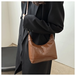 Detail of glossy brown crescent bag featuring marsche embossed texture and leather strap