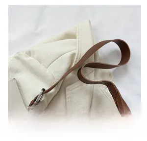 Detail of brown leather strap with silver metal buckle on a white textured blazer