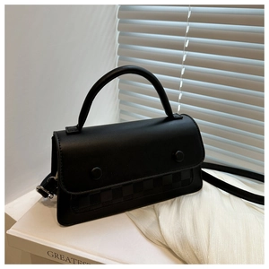 Detail view of black matte leather bag featuring checkered texture and round buckles