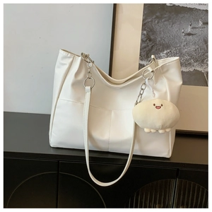 Close-up of white tote bag with silver chain strap and cute plush charm detail
