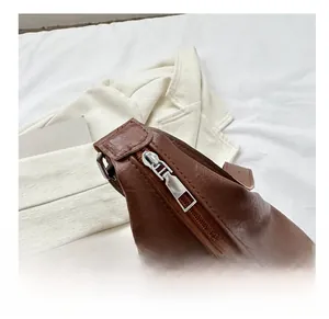 Close-up of smooth silver zipper hardware on retro brown leather crossbody bag