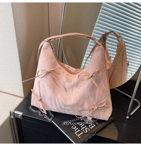 Détail du sac à main rose à nœuds avec texture plissée et chaîne en métal argenté