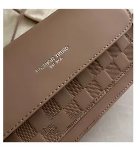 Detailed close-up of brown leather bag with checkered fabric and silver fashion lettering