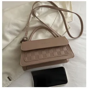 Detail of nude mini crossbody bag with checkerboard embossing and smartphone for scale