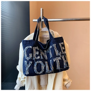 Dettaglio del logo Gentle Youth su borsa tote in denim retrò con toppe a bordi grezzi