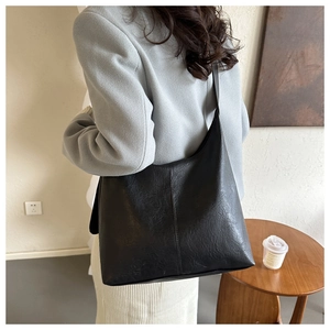 Detail of black large capacity shoulder bag showing textured synthetic leather and drape