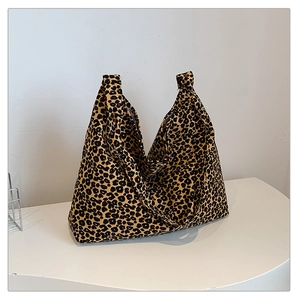 Close-up of large leopard print canvas tote bag on a minimalist white platform stand