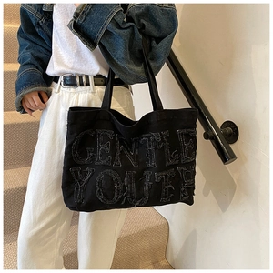 Dettaglio della borsa tote in tela nera con ricamo Gentle Youth in stile streetwear