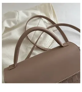 Detail of comfortable leather handle and checkered weave texture on brown crossbody bag