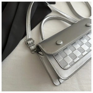 Macro shot of silver textured handbag featuring checkered embossing and rivet hardware