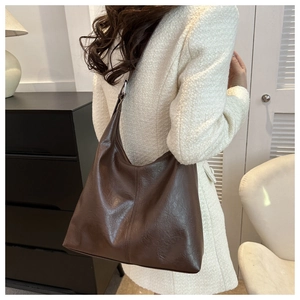 Close-up of a vintage dark brown tote bag on model showing soft leather texture