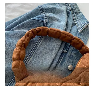 Gros plan sur un sac bandoulière matelassé marron avec rembourrage doux sur du denim