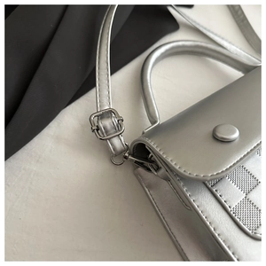 Detail of silver metallic handbag showing the grid texture and adjustable shoulder strap
