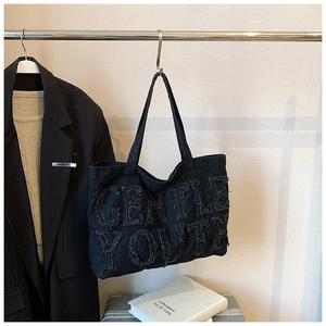Dettaglio della borsa tote in denim nero con scritta Gentle Youth per uno stile vintage