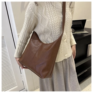 Detail of soft dark brown leather tote bag with natural texture shown on a model