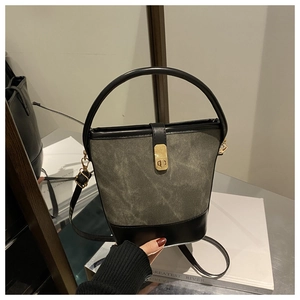 Detail of green canvas bucket bag with black leather patchwork and gold metal handle