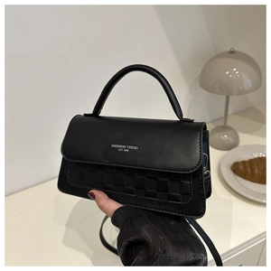 Detail of black faux leather crossbody bag with woven texture and silver lettering
