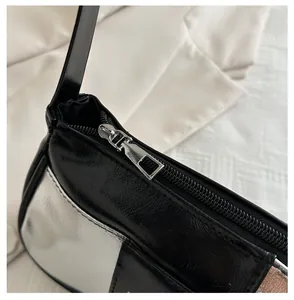 Detail of smooth metal zipper and silver-black patent leather contrast on the handbag