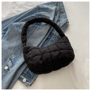 Close-up of black quilted cloud bag with square embroidery on white fabric background