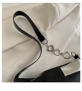 Detail of contrast handbag featuring decorative silver floral chain and glossy finish