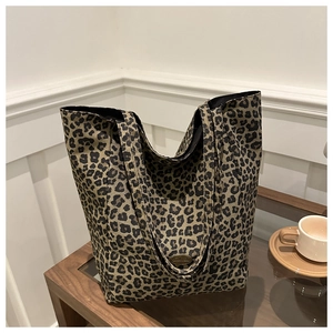 Détail du sac cabas léopard avec une plaque en métal handmade sur une table